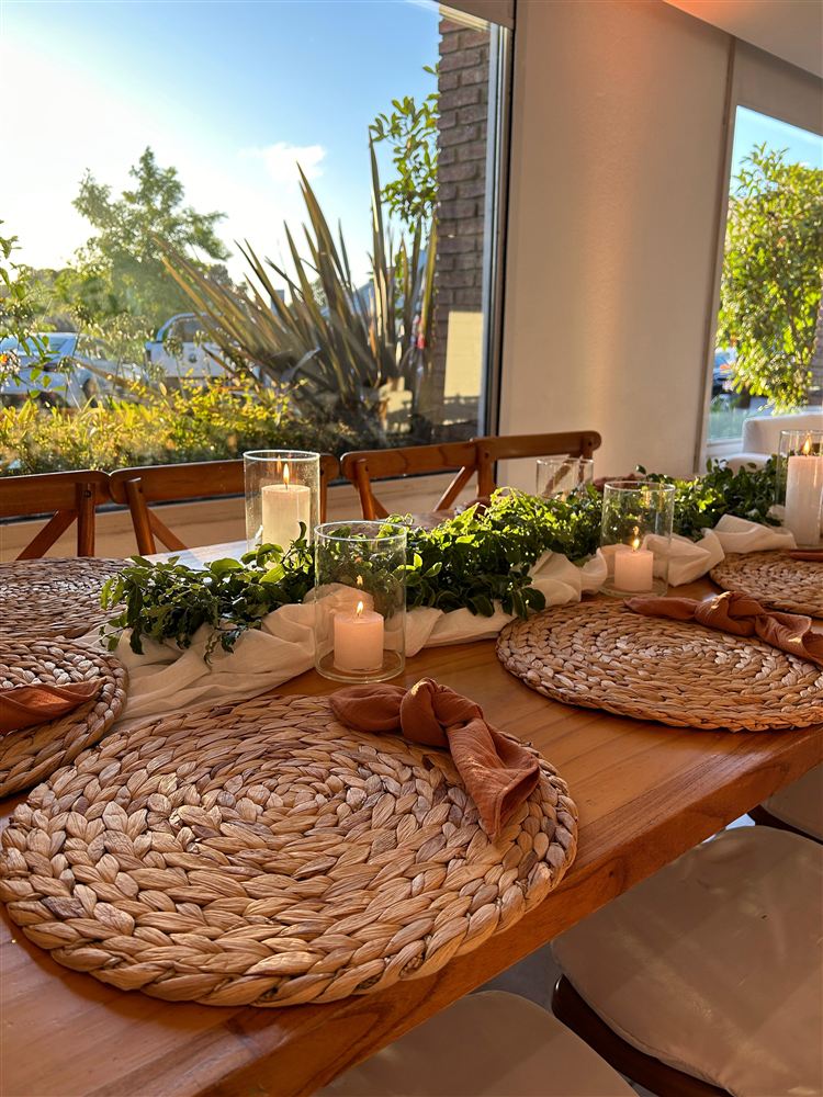 Mesa tejida con velas y guirnalda verde a la luz del día