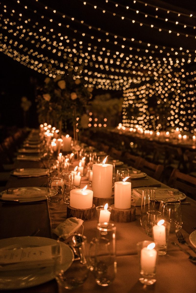 Mesa larga de evento con velas de parafina y luces cálidas